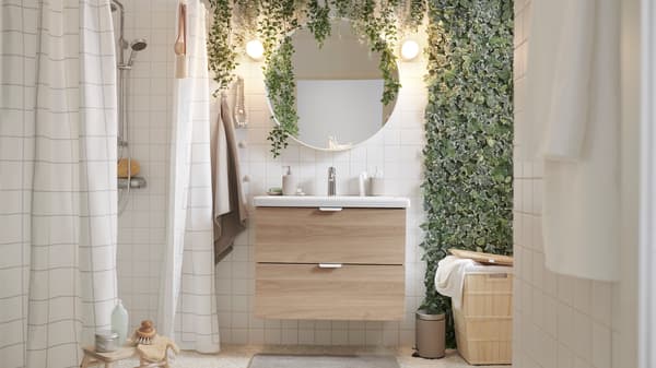 Baño con muebles GODMORGON. Hay toallas azules en ambos costados y una planta en la ventana.