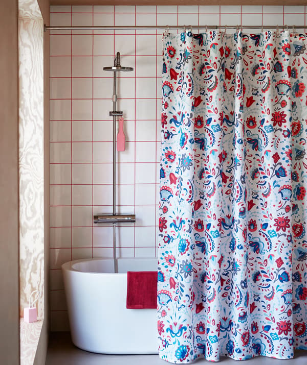 Bathroom interior with a richly patterned shower curtain hanging in front of a bathtub.