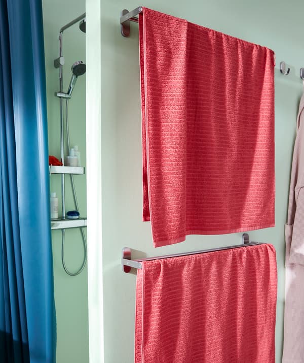 Bathroom with a shower as a recess behind a partial wall. Two racks of towels are fitted on the outside of the shower wall.