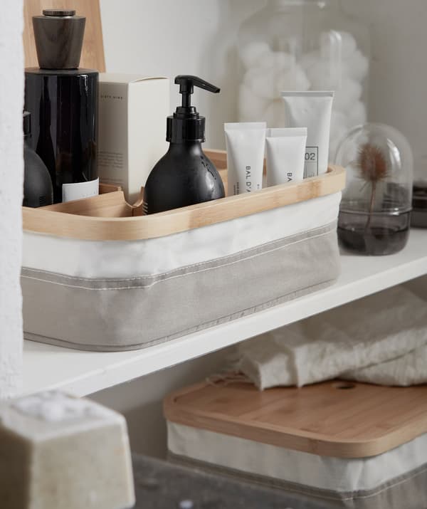 Beauty products ordered in a box with compartments, sitting on a wall shelf together with other storage.