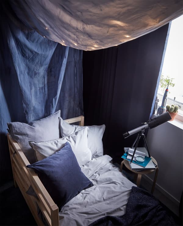Bedding and ÄNGSLILJA pillowcases. A frame bed and dark blue-dyed fabric canopy and block-out curtains.
