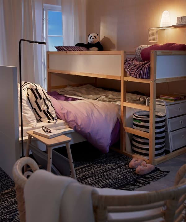 Bedroom interior with a loft bed standing across a lower bed, as a child’s bed straddling the parents’.