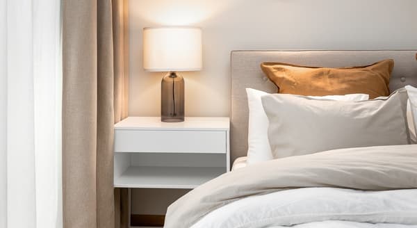 Bedroom nightstand with modern lamp and neutral decor