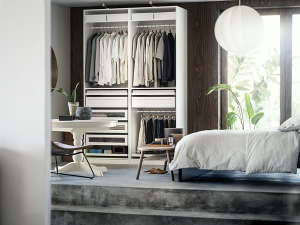 Bedroom space with an open wardrobe and white duvet covers on the bed