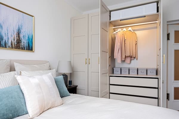 Bedroom wardrobe with open doors showing neatly organized clothes and boxes