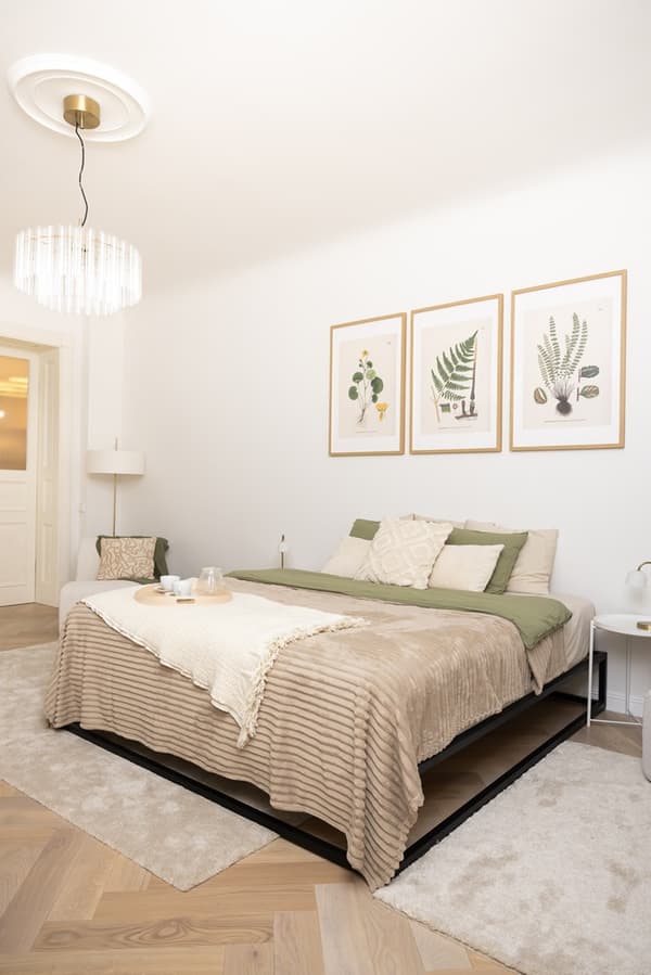 Bedroom with a double bed, neutral textiles, wall art and a ceiling lamp.