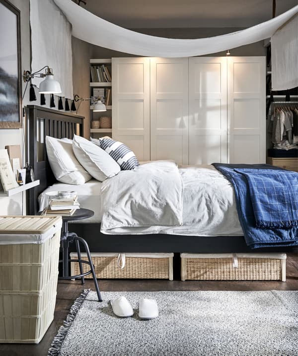 Bedroom with airy feel, natural materials and a simply arranged canopy hung over the bed. Wardrobe along the back wall.