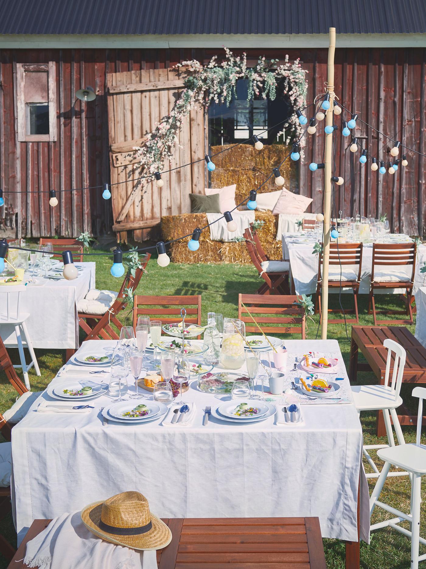 Bei einer Outdoor-Party werden die Tische mit GULLMAJ Tischdecken, UPPLAGA Tellern, DYRGRIP Gläsern und UPPHÖJD Besteck gedeckt.