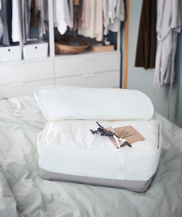 Bekas storan terletak di atas katil, di dalamnya terdapat duvet tebal bersama dengan nota yang ditulis dengan kemas dan beberapa ranting lavender.