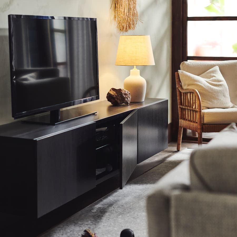 BESTA TV console bench in living room with table lamp, arm chair and sofa set with rug on the floor.