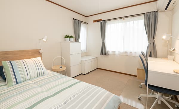 ベット、机、引き出し置いてある整理された部屋。
