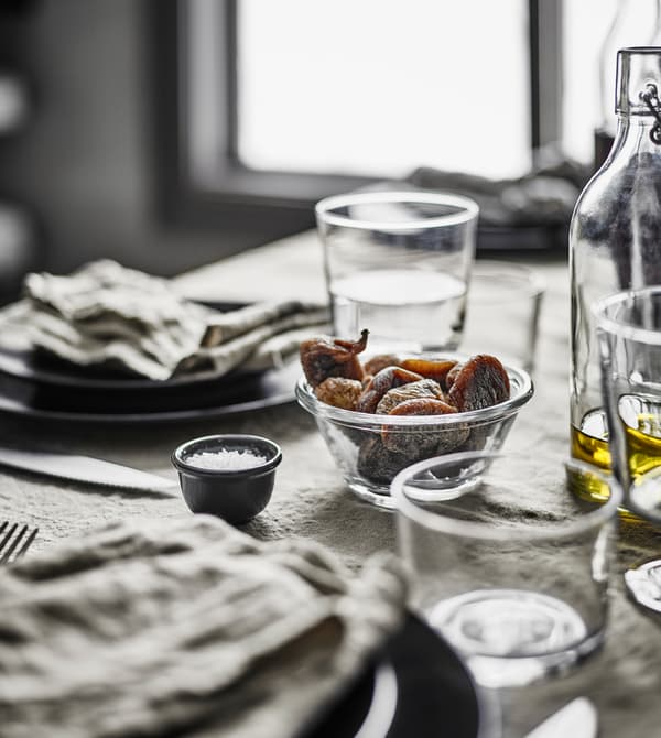 Bicchieri in vetro trasparente e stoviglie grigio scuro su un tavolo da pranzo rustico moderno - IKEA.