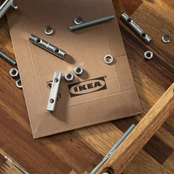 Bild tagen uppifrån på reservdelar och en IKEA kartiong som ligger på ett trägolv.