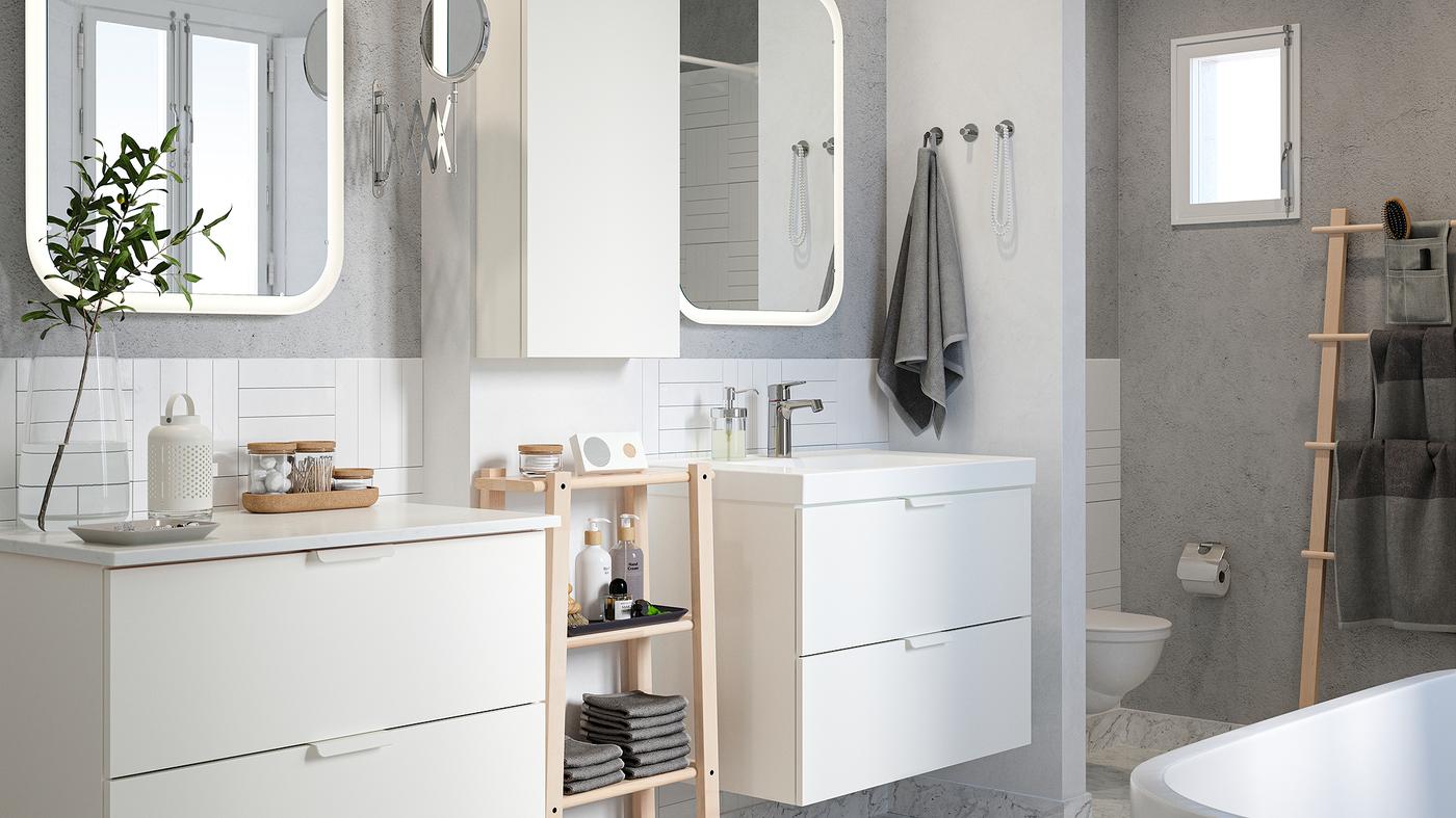 Bilik mandi berjubin putih dengan dinding berwarna kelabu, dua kabinet sink, cermin dan para-para buatan kayu birch dengan tuala dan produk kecantikan.
