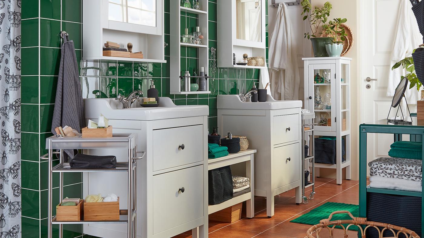 Bilik mandi dengan jubin hijau, dua sink HEMNES berwarna putih dan kabinet cermin, tuala dan aksesori diperagakan.