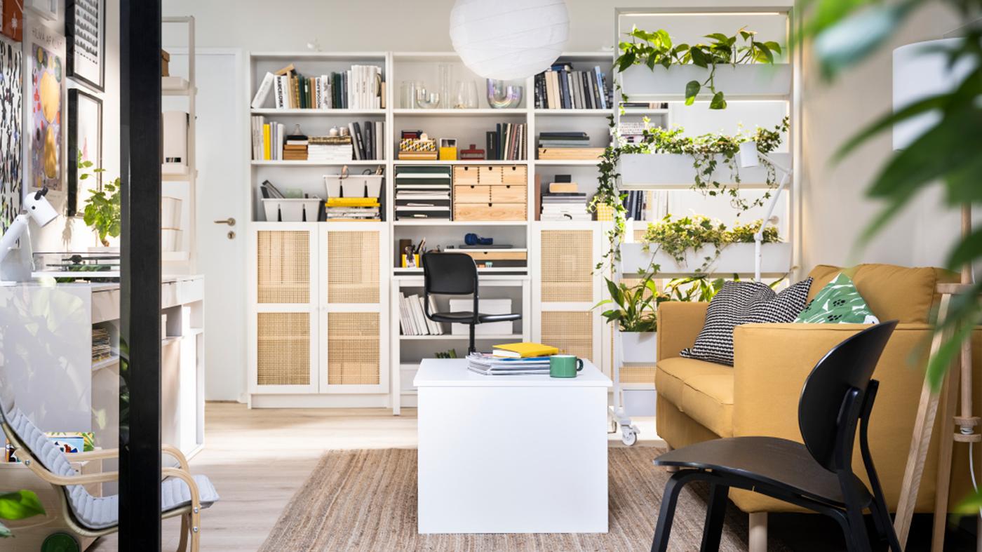 BILLY bookcases against a wall behind a MITTZON frame with castors, an ÖSTAVALL adjustable coffee table and a PÄRUP sofa.