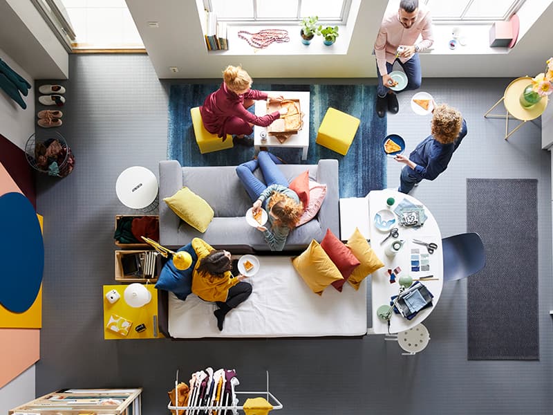 Bird eye view of a living room with people sitting around eating pizza