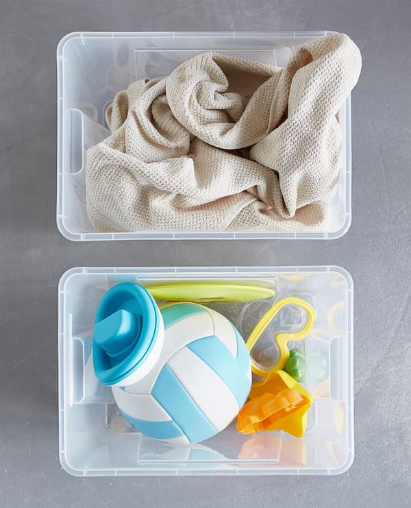 Bird’s-eye view of two plastic storage boxes filled with towels and other beach gear.