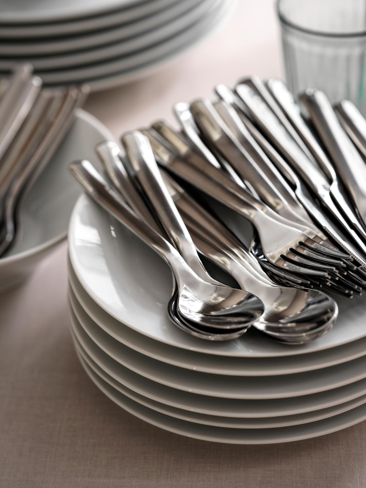 ベージュのテーブルクロスをかけたテーブルに、プレートやグラス、IKEA 365+ カトラリー、その他の食器が積み重ねてある。