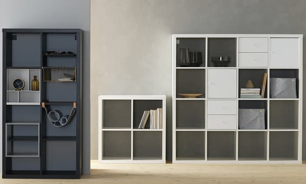 Black and white KALLAX shelves with square boxes. Some compartments are open, showing books and shelves. Others are closed compartments with boxes.