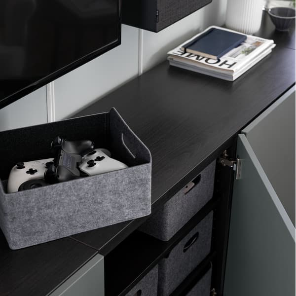 Black BESTÅ cabinet with an open door with grey storage boxes.