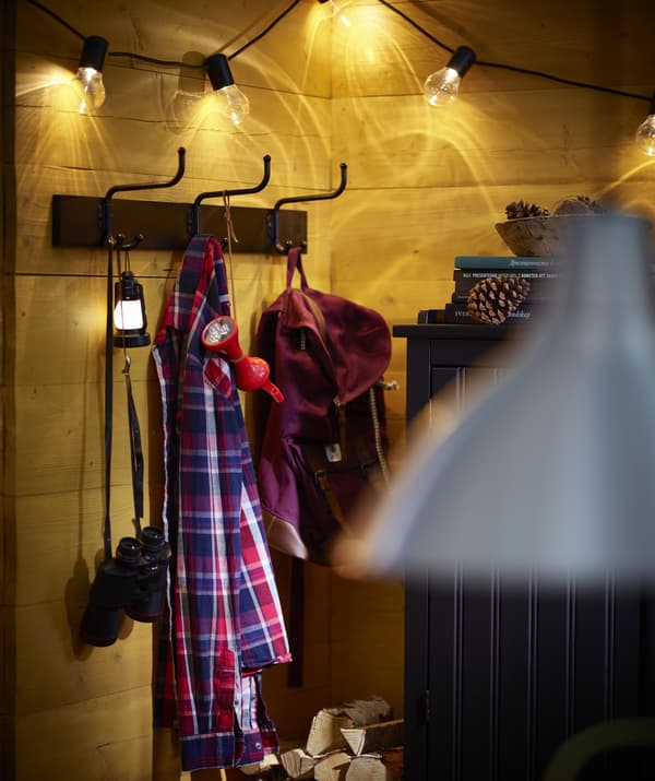 Black PINNIG rack with three hooks holding red and blue jackets and other accessories