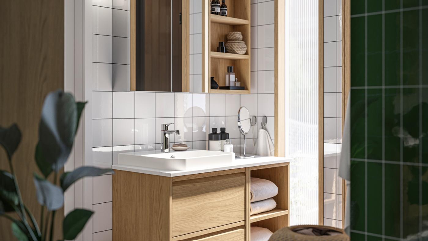 Blick in ein Badezimmer mit ÄNGSJÖN Fronten in Eichenachbildung. Es bietet einen Waschbeckenschrank mit offener und geschlossener Aufbewahrung sowie einen Spiegelschrank.