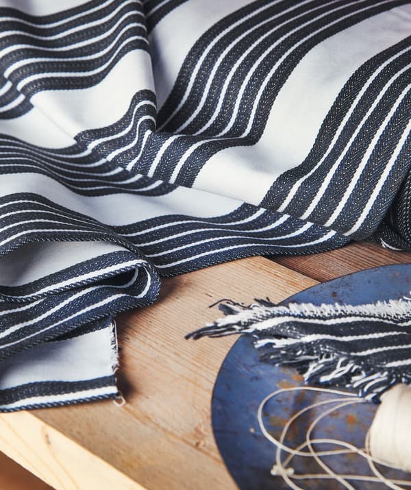Blue and white striped fabric and a blue plate on a wooden table top.
