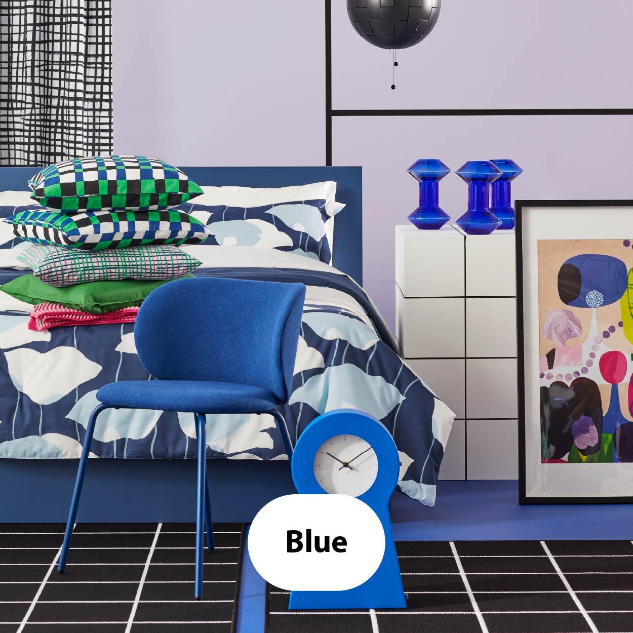 Blue – Modern bedroom with deep blue chair, patterned bedding in shades of blue and white, and bold geometric wall art.