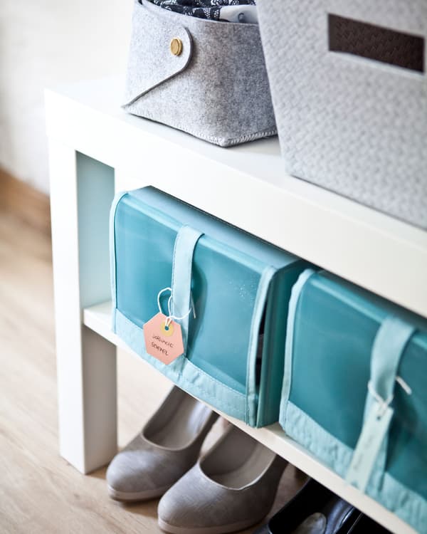 Blue shoe storage boxes on the shelf of a white shoe bench.