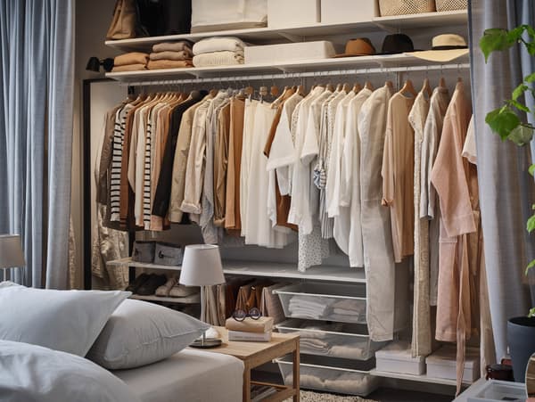 BOAXEL storage system with lots of hanging clothes on a clothes rail, more clothes and hats lie on shelves and in baskets.