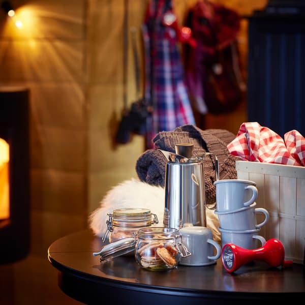 Bocaux en verre, chopes grises, articles textiles et lampe de poche déposés sur une table ronde