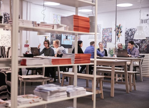 Bookshelves, wall art and people working in groups on long tables.