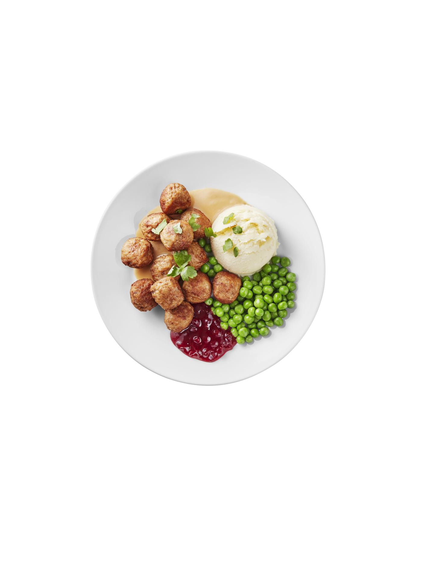 Bord met gehaktballetjes, aardappelpuree, groene erwten en roomsaus, afgewerkt met rode confituur.