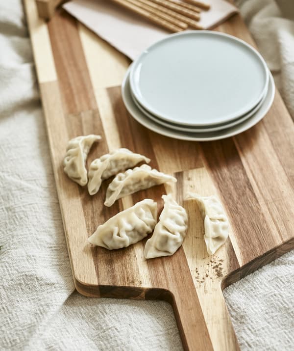 Bouchées et assiettes sur une planche à découper en bois.