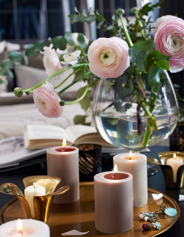 Bougies allumées et fleurs coupées sur une table.