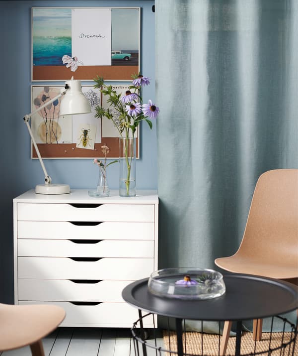 Bouqets of flowers in vases on a drawer unit next to a white work lamp