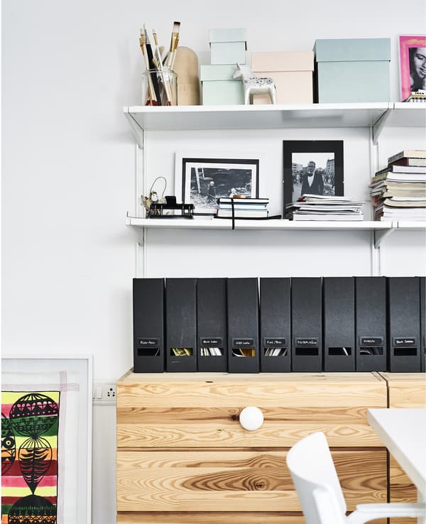 Box files and shelves above a wooden chest of drawers.