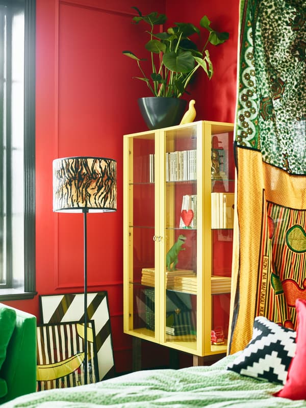 Bright green coloured furniture and red walls help make this stylist’s dream bedroom come together.