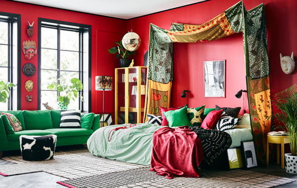 Bright textiles, colourful furniture and red walls help give this bedroom its distinctive look.