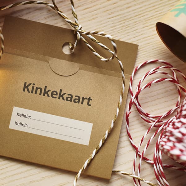 Brown gift card envelope with text “Kinkekaart” and decorative twine on a wooden table.