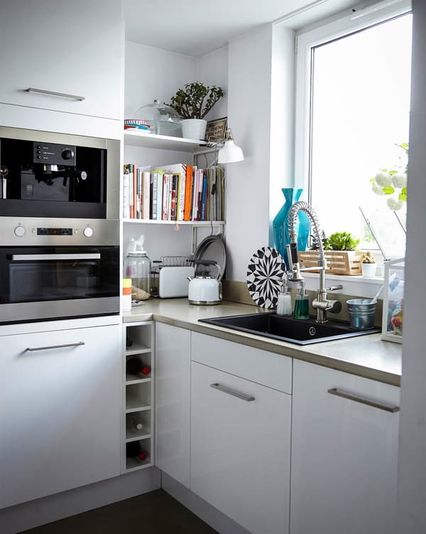 Built-in appliances, including an oven mounted in a high cabinet, in a bright, white, family-friendly kitchen.