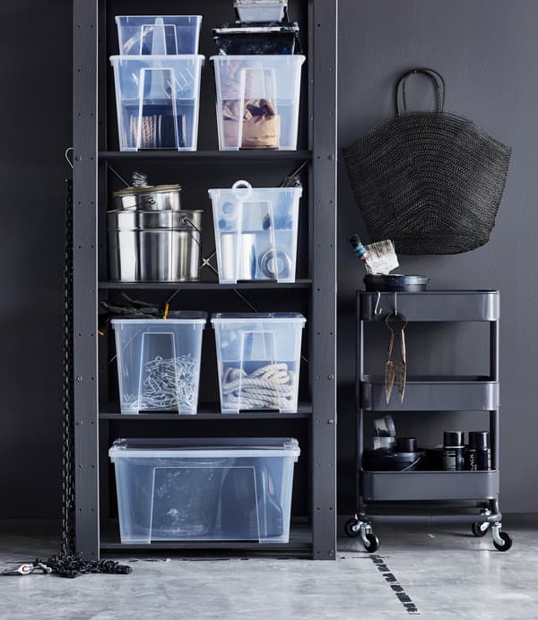Bulky items are stored in large, clear IKEA SAMLA boxes on shelves, beside an IKEA RÅSKOG trolley.