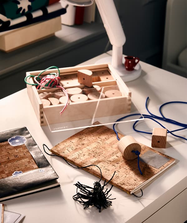Bureau avec travail en cours: couvertures de cahier personnalisées avec autocollants, et signets confectionnés avec des perles à enfiler.