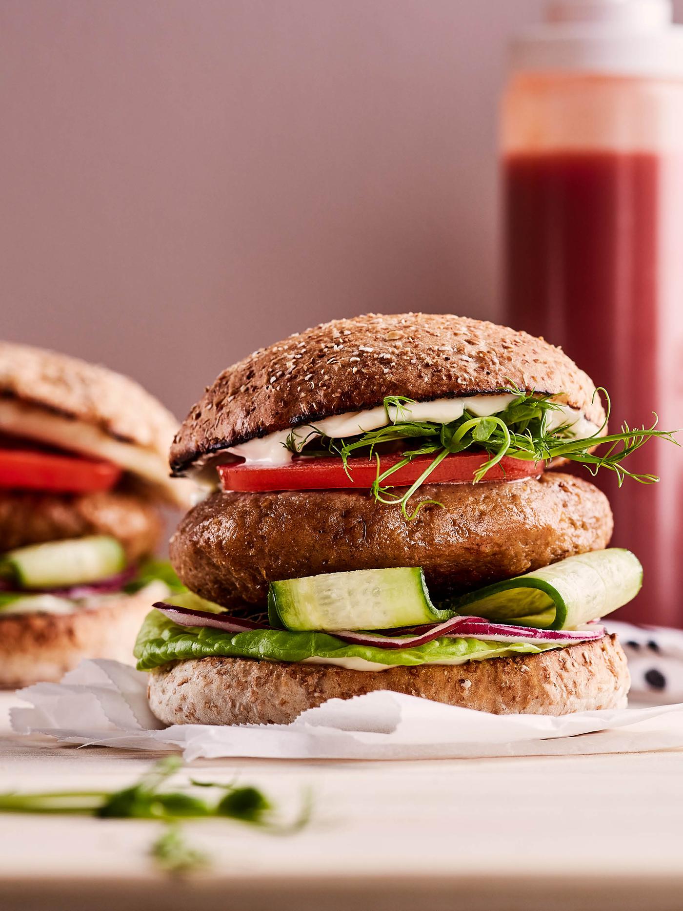 Burger vyrobený z bezmasé směsi VÄRLDSKLOK s okurkou, červenou cibulí, hlávkovým salátem, rajčaty, klíčky a majonézou.