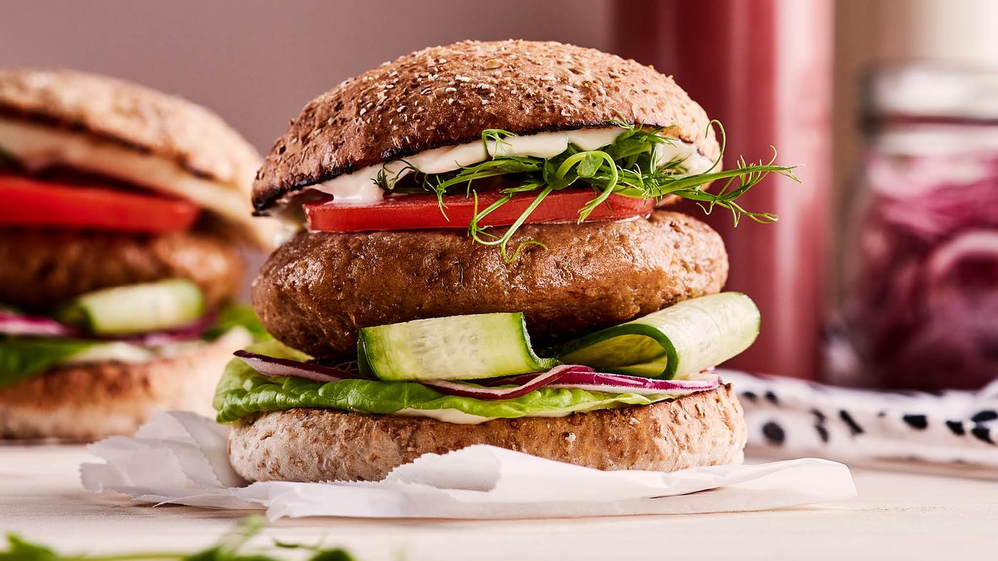 Burger vyrobený z bezmasé směsi VÄRLDSKLOK s okurkou, červenou cibulí, hlávkovým salátem, rajčaty, klíčky a majonézou.