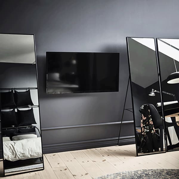 Cachez une TV fixée au mur en plaçant devant des miroirs intégraux. Nous avons utilisé trois miroirs IKEA KARMSUND, qui mesurent 167 cm de haut et ont un cadre et des pieds en acier laqué par poudrage noir. Pour regarder la télé, déplacez-les simplement.