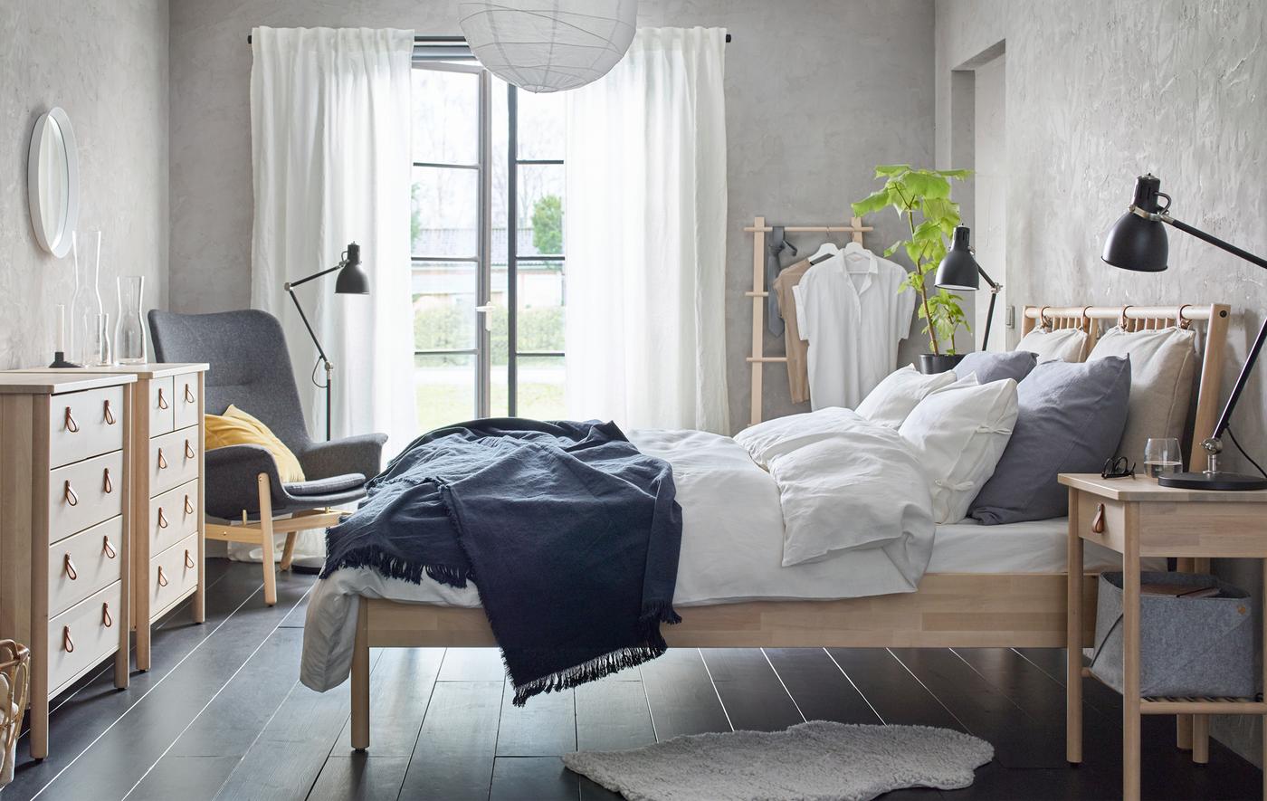 Camera da letto in tonalità neutre con struttura letto, cassettiera e comodino in legno - IKEA