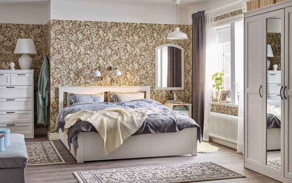 Camera da letto tradizionale beige, azzurra e bianca con carta da parati floreale e letto, comodino e cassettiera SONGESAND bianchi – IKEA