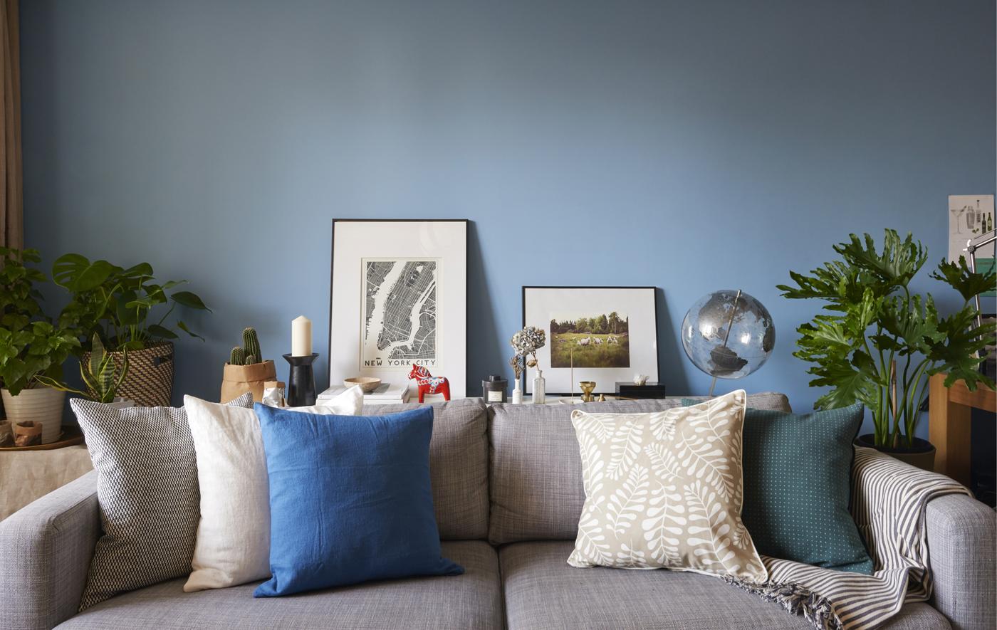 Canapé gris avec coussins, adossé à un mur bleu.
